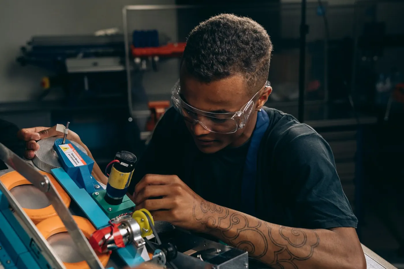 A young engineer in safety glasses adjusting machinery